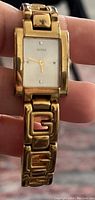 Gold-tone Guess watch with rectangular face and linked G design bracelet.