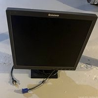Front view of Lenovo 17 inch computer monitor on black stand with VGA cable and power cord on floor.