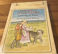 Front cover of a used softcover book titled 'The First Four Years' by Laura Ingalls Wilder with an illustration of a pioneer family and dog.