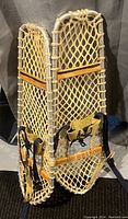 Pair of vintage Lacrosse aluminum snowshoes standing upright showing aluminum frames, webbing, bindings and wooden trim.