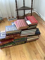 Overview of two stacks of leather-bound hardcover books with gilt decoration, various colors