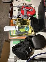 Items arranged on table including Sony headphones in case, Sony Cyber-shot camera pouch, multiple electronic accessories and packs of chargers and adapters.