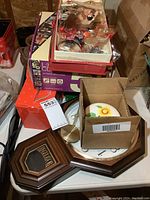 Wooden wall clock, ceramic urn boxed with sunflower design, digital photo frame box, and assorted knick knacks on table