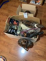 Box filled with assorted collectibles and figures showing several items inside and a wood keg with shot glasses outside the box
