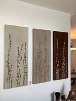 Set of three vertical rectangular fabric art panels hung on a white wall shown as a group capturing design and color tone contrast.