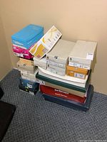 Stack of multiple shoe boxes from various brands and sizes, including blue, pink, orange, and white boxes.