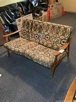 Front view of the loveseat showing patterned cushions and wood frame.