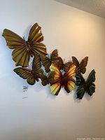 Full view of the 7 metal butterfly wall decorations arranged on a white wall.