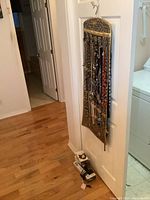 Leopard print closet hanger hanging on a white door, displaying multiple necklaces on both sides.