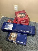 Boxes of new crystal glassware from Cristal d'Arques and RCR Opera stacked on floor.