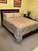 Full assembled queen bed with bedding, mattress and box spring visible under comforter