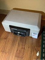 Closed Sentry 1100 fire safe with key in lock and manufacturer label with dimensions.