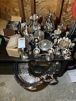 Wide view of assortment of silver plate items on table and large tray underneath
