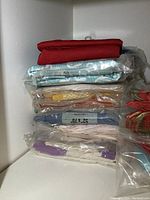Stack of several sealed folded tablecloths and table linens in various colors and patterns including a red cloth on top