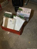 Box containing new tablecloths and hand towels along with the AeroGarden kit box on the floor.