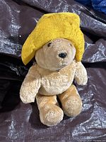 Front view of the plush Paddington Bear wearing a yellow felt hat.