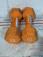 Pair of orange neoprene dumbbells with hexagonal ends showing the number 8 indicating 8 pounds each.