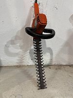 Full view of the electric hedge trimmer with blades and handle guard visible.