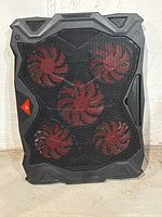 Front view showing the entire rectangular black cooling pad with five red fans through mesh grille.