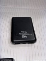 Backside of the power bank showing detailed model information including input 5V=1A, output 5V=2.1A, battery capacity 5000mAh, certification logos (CE, FC), and manufacturer details.