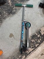 Full view of Razor scooter folded on ground showing the chrome frame and green foam handle grips