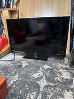 Front view of RCA 32" LED LCD HDTV showing entire screen and stand base on floor.