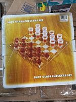 Original packaging for shot glass checkers set showing the fully assembled game with shot glasses arranged on the board.