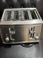 Top front view showing four wide slots, two toasting levers, control dials, and Black & Decker logo with visible use marks.
