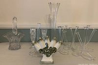 Wide view of all bud vases including glass basket, tall glass vase, ceramic fan-shaped vase, and six clear glass tulip-shaped vases.