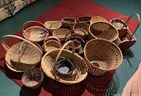 Wide view of multiple baskets on carpet including round, oval and rectangular shapes, with some featuring handles.