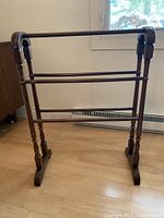 Full front view of antique solid wood blanket rack showing three horizontal bars for hanging textiles.