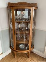Front view of refinished solid oak china cabinet with three glass panels showing interior shelves and decorative items.