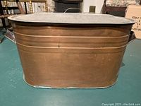 Front view of the oval copper boiler showing its shape, handles, and patina on the copper surface.