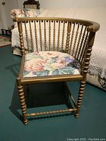 Front angle showing the turned spindle legs and back of the gold painted corner chair with floral upholstered seat cushion.