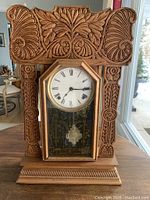 Front view of the carved oak gingerbread clock showing elaborate woodwork and Roman numeral clock face.