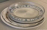 Stacked oval platters showing glass and china pieces with detailed edge and pattern designs
