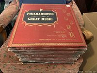 Stack of 19 red albums labeled Philharmonic Family Library of Great Music, including volumes 1-18 and 20