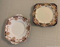 Two square serving plates displayed on a tiled surface showing decorative edges and patterns.