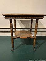 Front view of square-top side table with dentil molding apron, turned legs and lower shelf