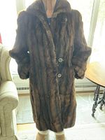 Full view of a vintage women's muskrat fur coat hanging showing length and button closure.