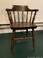 Front view of wooden banker's chair showing curved back with spindles and solid seat.