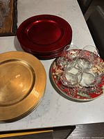 12 gold and 12 red chargers stacked, ceramic cookie tray beneath stemless wine glasses