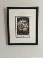 Framed linocut print titled 'Daisy' showing two daisies in textured black and white, with matting and black frame.