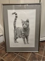 Full view of framed black and white cat print showing the entire artwork including mat and frame, standing on tiled floor.
