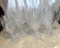 13 crystal goblets on marble surface: 5 wine goblets and 8 water goblets featuring distinct vertical cut patterns and textured stems.