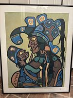 Framed Norval Morrisseau art print showing stylized figures with bold colors and patterns.