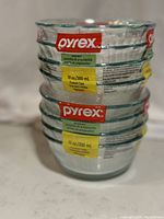 Stack of eight clear glass Pyrex prep bowls with red and yellow labels, showing brand and volume information.