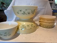 Set of three cream-colored Pyrex mixing bowls with green Shenandoah floral vine pattern, showing different sizes and the Cinderella spout bowl.