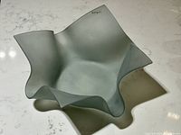 Top view of frosted glass handkerchief bowl showing folds and artist signature on edge.