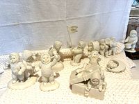 Overall group of Snowbabies porcelain figurines showing children in textured winter outfits, some holding instruments, a flag dated 2001, and other playful poses.